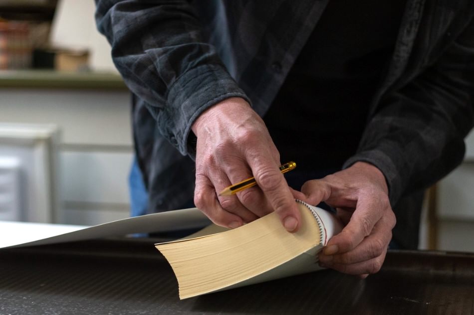 Nahaufnahme eines Buchbinders bei der Handarbeit – Einband wird manuell angepasst und überprüft
