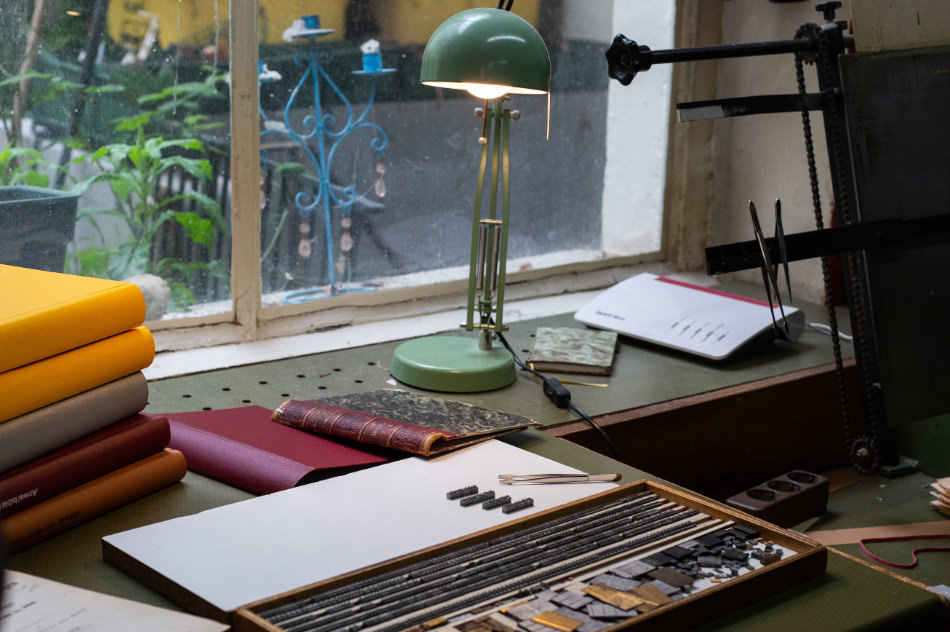 Buchbinder-Arbeitstisch mit Werkzeugen und Materialien in einer traditionellen Werkstatt.