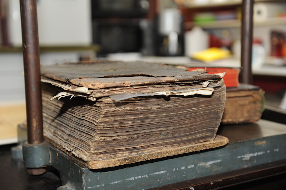 Historisches, beschädigtes Buch in einer Presse zur Restaurierung.